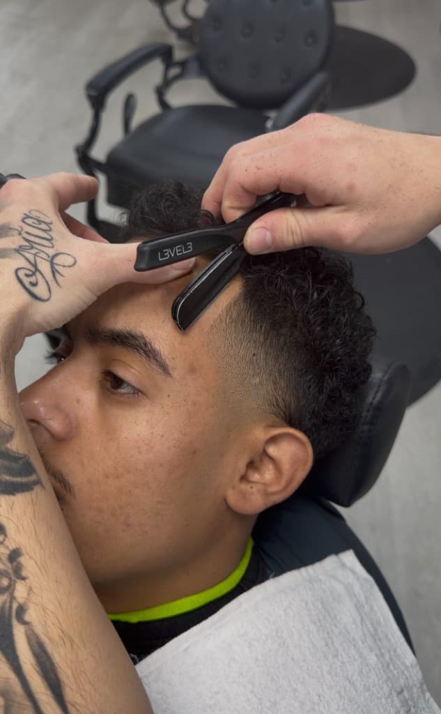 Barber performing precision razor line-up edge work at The Barber Lounge